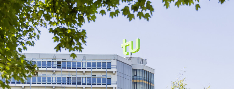 Mathetower mit TU-Logo umrahmt von Bäumen